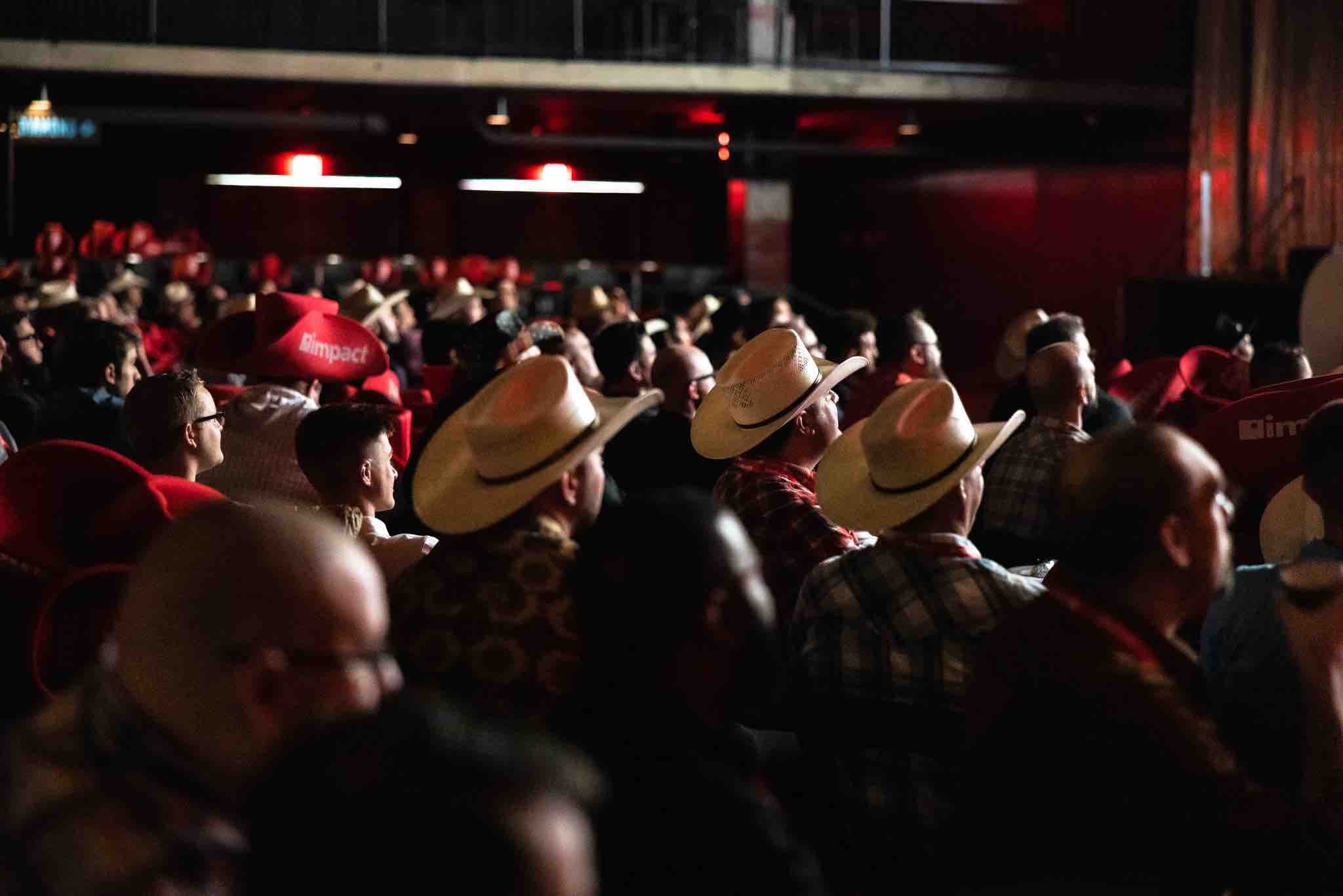 an audience of people sitting in chairs from behind with some of them wearing cowboy hats