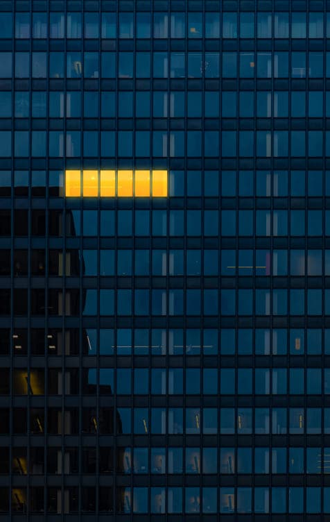 Small line of lights on in a tall office building with most other lights turned off