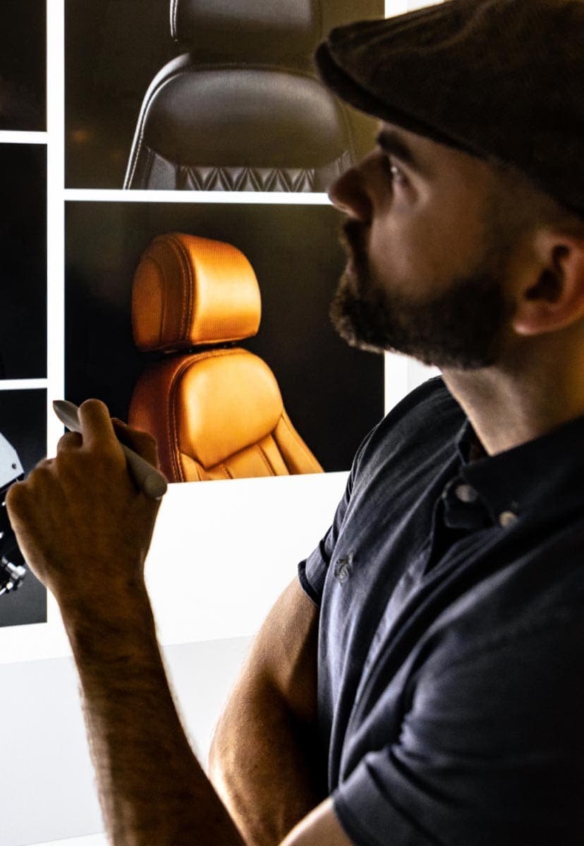 A man looking at a wall covered in photos of an office chair