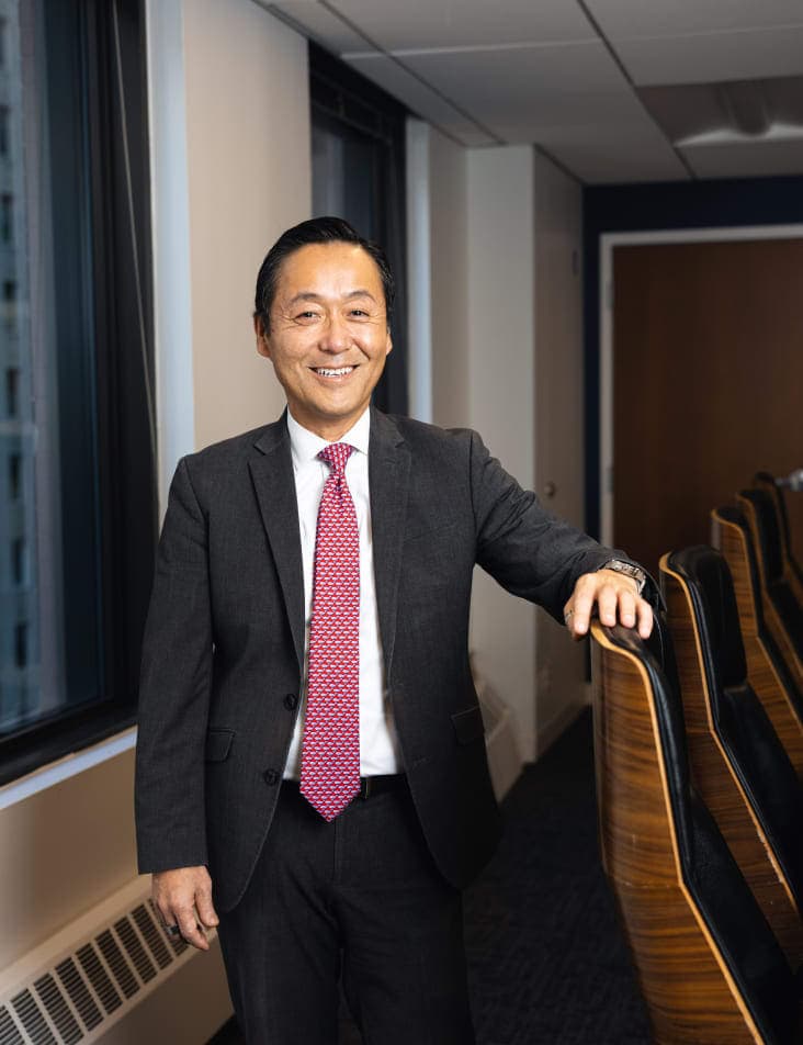 man wearing suit standing with arm on office chairs in office building