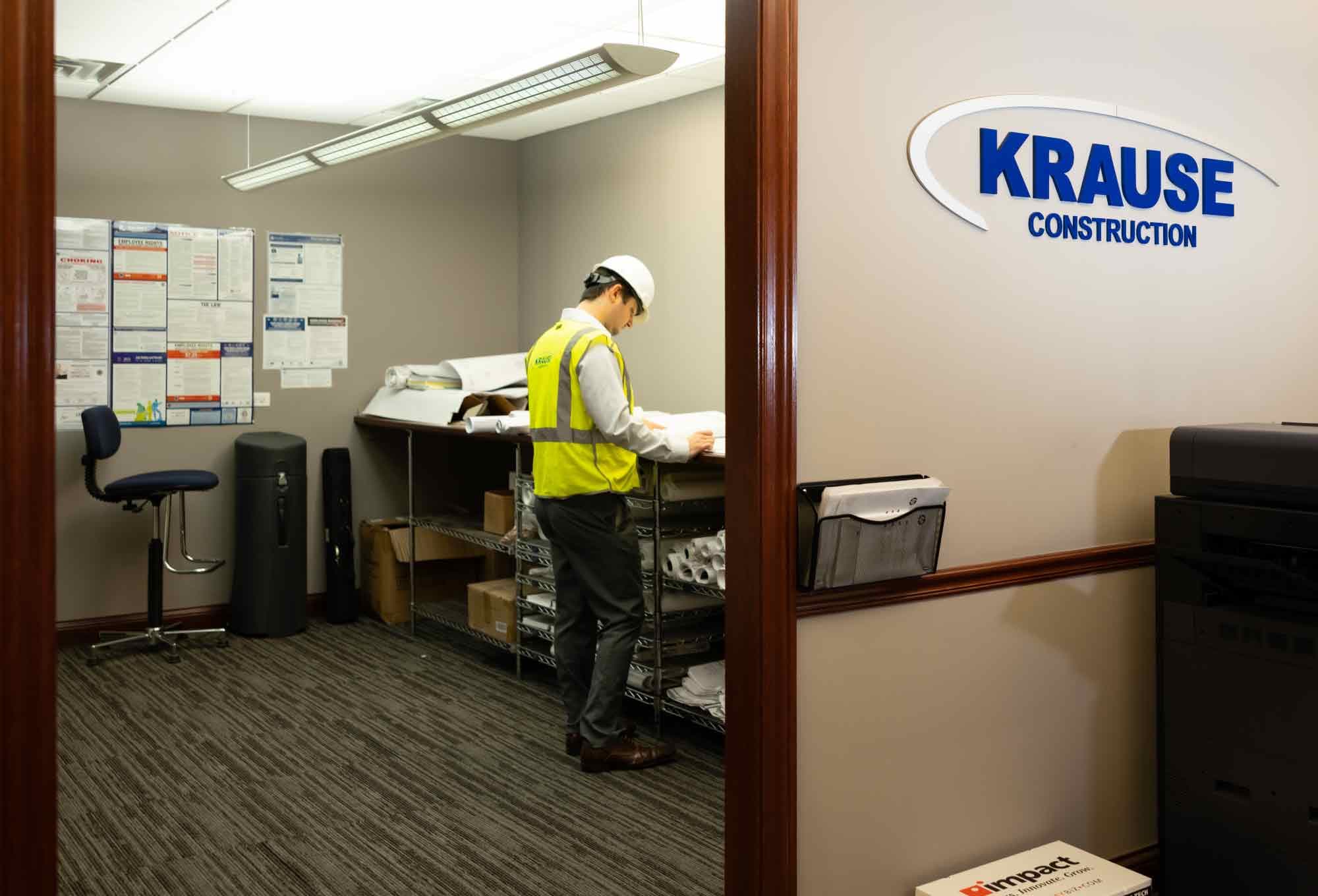 A construction worker reading a blueprint in a Krause Construction office