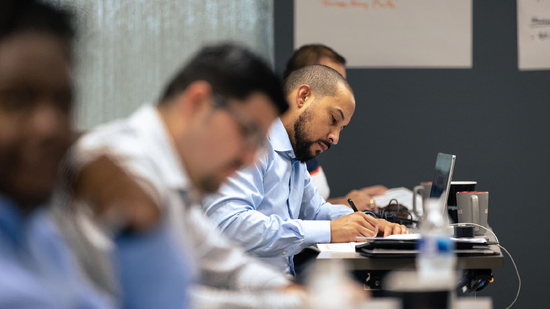 A line of professionals working at a long classroom table