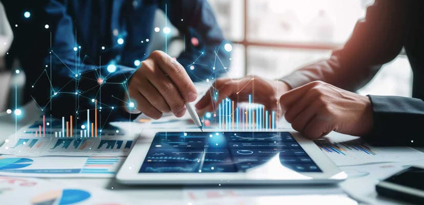 Two people's arms and hands working on a tablet with graphics of data floating around them