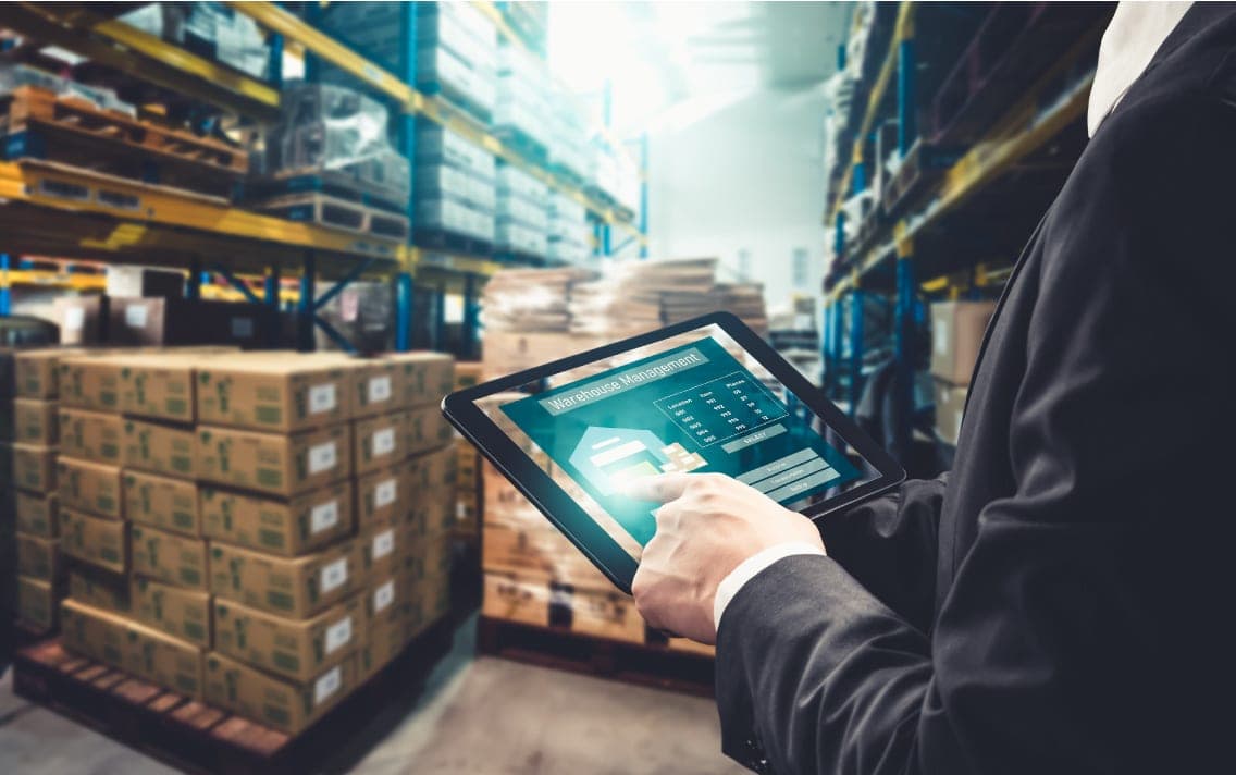 A person in a warehouse doing work on a futuristic tablet