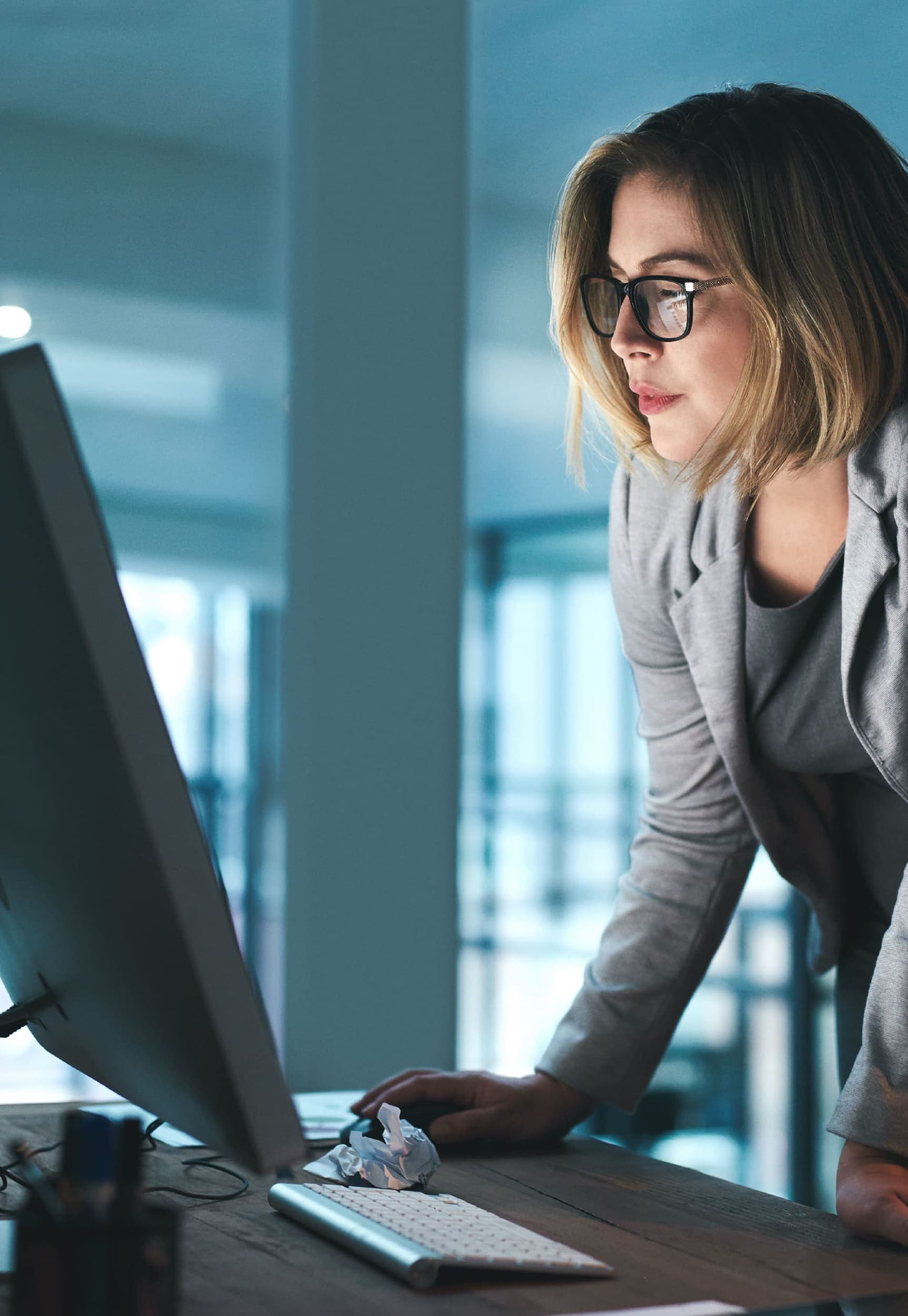 Woman standing over a computer, looking at something on the screen