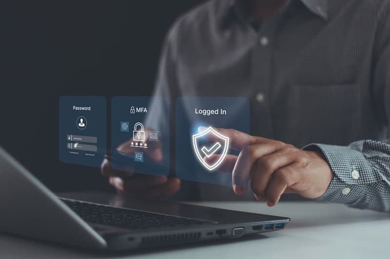 man working on laptop pressing holographic buttons that say logged in and MFA