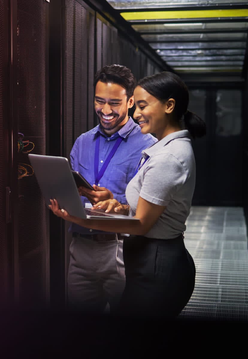 two people working on a laptop in a server room