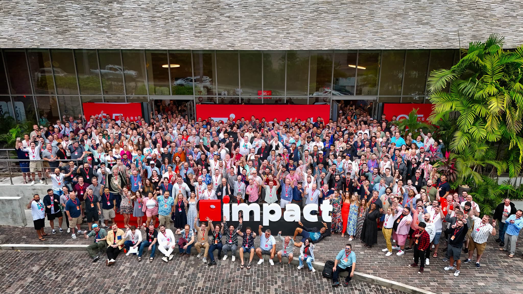 large group of happy people around Impact sign