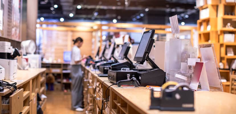 Behind the counter at a store with a woman working one of the cash registers