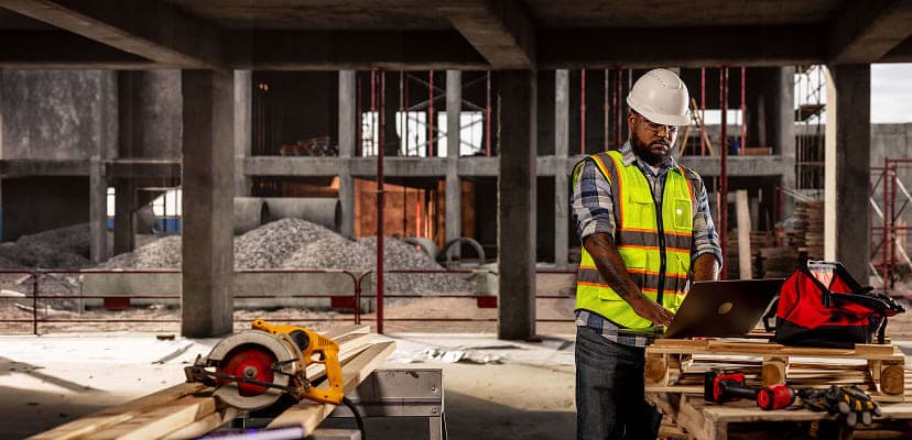 A construction worker on site working on a laptop
