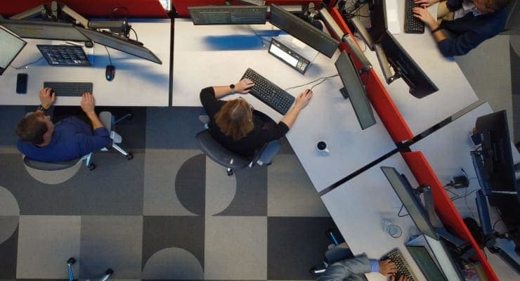 Overhead shot of people working at connected desks on computers