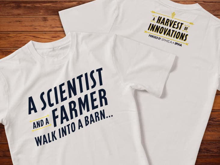 White t-shirts with “A scientist and a farmer walk into a barn” on the front and a logo on the back.