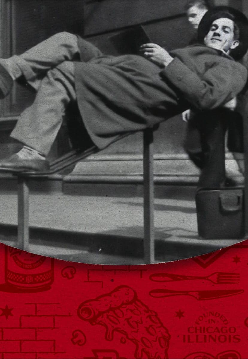 Angelo Garetto, the founder of Beggars Pizza, resting on the handrail of the Art Institute of Chicago while reading a book.
