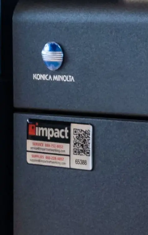 Impact's logo and QR code underneath a konica minolta badge on a printer
